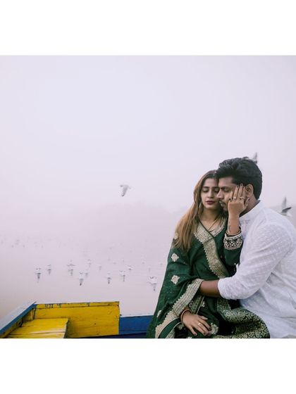 A candid, atmospheric shot from a pre-wedding session on the water. The foggy weather and the birds in the background add a unique, cinematic quality to this intimate couple's portrait.