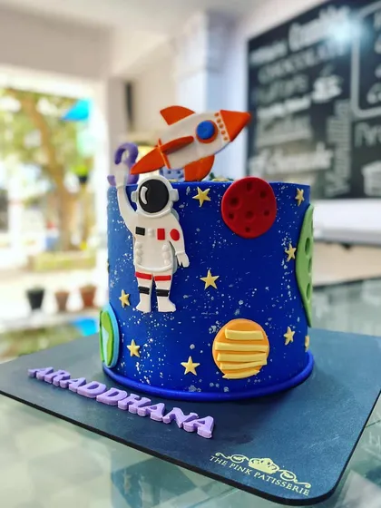An out-of-this-world space-themed cake. The deep blue design features an astronaut, a rocket, and planets, perfect for a future space explorer's birthday.