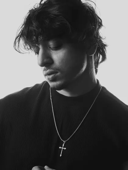 Another angle of the thoughtful black and white portrait. The focus on detail, like the cross necklace, adds a personal touch.