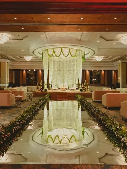 For a grand ballroom reception, we designed a sophisticated and elegant experience. The layout features a central water body reflecting a magnificent floral chandelier, surrounded by plush lounge seating, transforming the entire space into a luxurious indoor garden.