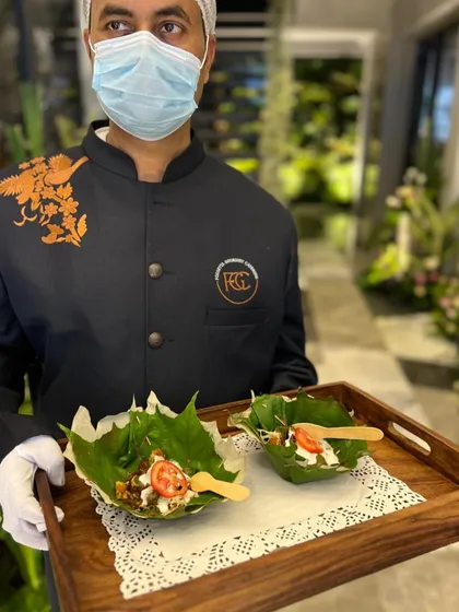 We prioritize eco-friendly and stylish presentation. Here, an appetizer is served in a natural leaf bowl, held by our server, combining sustainability with an elegant, rustic aesthetic.