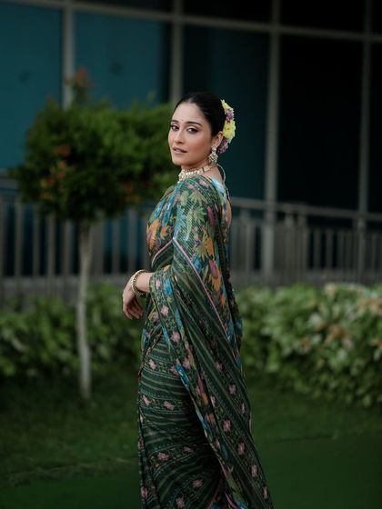 A candid-style portrait of an actress in a floral green saree, capturing a natural glance over the shoulder. This shot is perfect for lifestyle features, blending elegance with a relaxed feel.