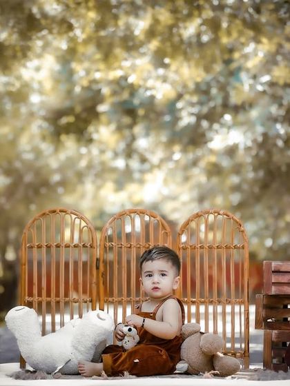 A handsome little man in a rustic outdoor setting for his first birthday portraits. The warm, golden light of the background gives the photo a dreamy quality.