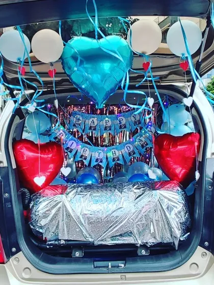 A cheerful car trunk decoration with a blue, white, and red color palette. This surprise includes a "Happy Birthday" banner, foil heart balloons, and festive ribbons.