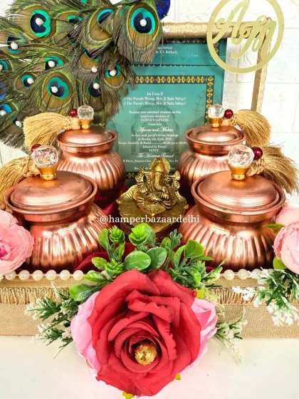 Our grand wedding invitation hamper, designed to be a gift in itself. It features a wedding card, a Ganesha idol, four metallic jars with dry fruits, and is decorated with real peacock feathers.