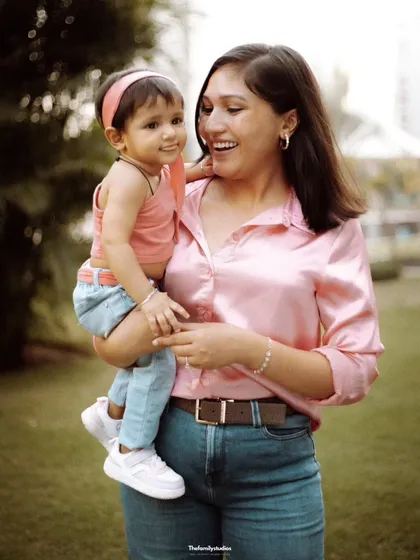 A mother holds her smiling toddler in her arms during an outdoor portrait session. We focus on capturing the loving connection and happy expressions that define your family's bond.