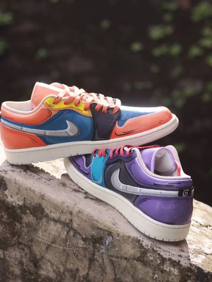 The Naruto and Sasuke custom Air Jordan 1s, shot outdoors. The natural light really makes the colors pop.