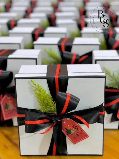 Another angle of our chic Christmas gift boxes. The clean white boxes are styled with black and red ribbons, a fresh green accent, and a custom holiday tag, perfect for a modern and stylish corporate gift.