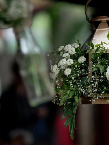 A close-up of the delicate floral decor for a Sangeet, featuring white roses and baby's breath in a hanging lantern.