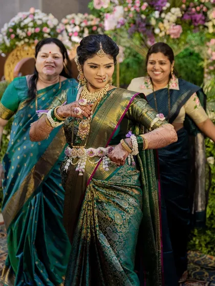 A joyful dance at a baby shower. The mom-to-be is wearing our custom floral armlets (bajuband) and a floral waist belt (kamarbandh) that beautifully accentuates her green Kanjivaram saree.