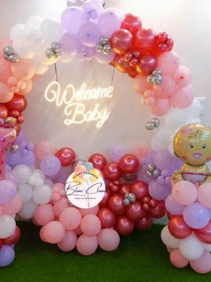 Another angle of the 'Welcome Baby' girl balloon arch, showing the balloon pillars and foil accents.