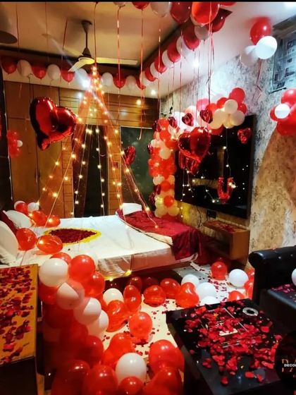 An elaborate Valentine's Day room decoration, with the entire room filled with red and white balloons, a light-up canopy, and rose petals covering every surface.