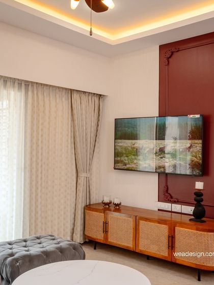 A closer look at the TV and media console, demonstrating how we balance statement pieces like the maroon accent wall with the natural warmth of wood and cane furniture.