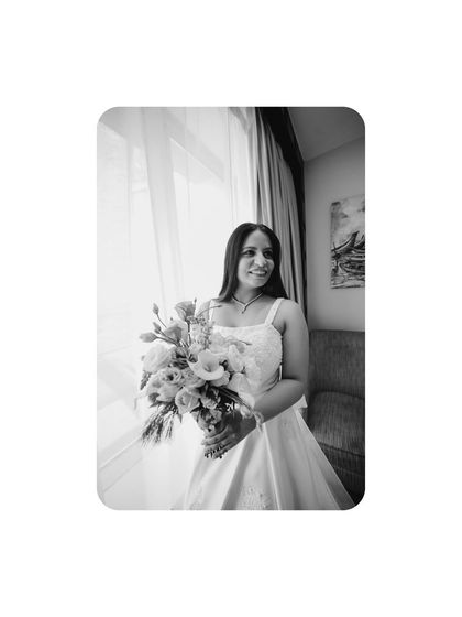 A beautiful black and white portrait of the bride by the window, capturing a moment of quiet contemplation and happiness.