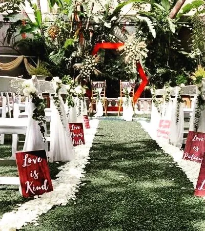 We create elegant and memorable pathways for your most special moments. This Christian wedding aisle is lined with fresh white rose petals and personalized signs, leading to a beautifully decorated altar in a lush garden setting.