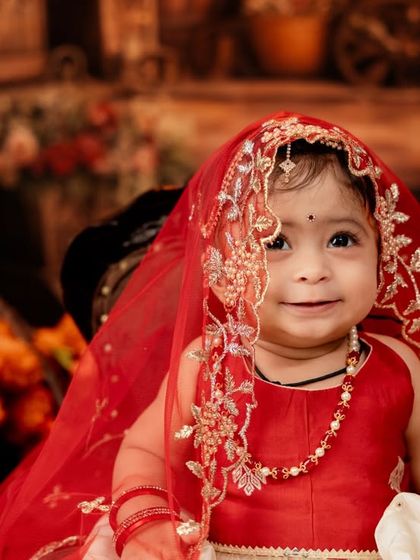 A close-up capturing the innocent and sweet expression of the baby girl in her traditional red outfit.