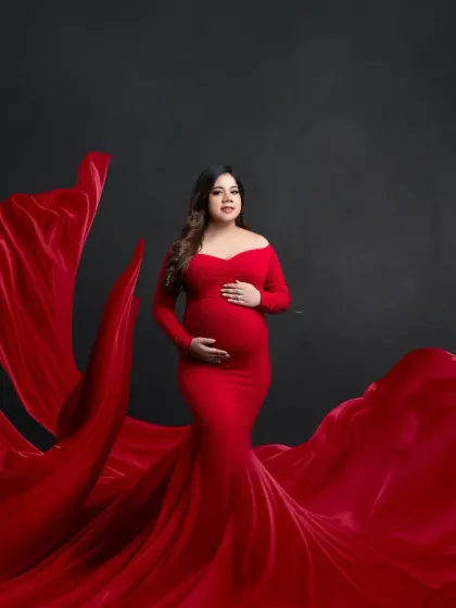 Elegance in motion. This portrait showcases a beautiful red gown with a long, flowing train, expertly arranged to create a sense of grandeur and movement.