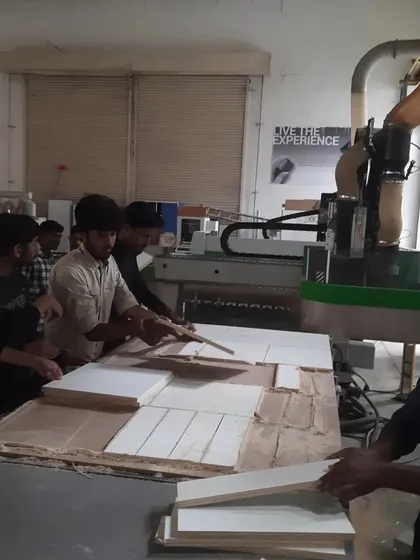 Students organize the various components of a cabinet that have been cut on the CNC panel saw, preparing them for edge banding and assembly.