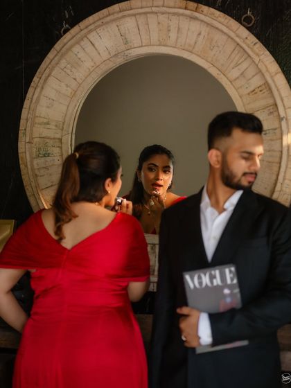 A creative and playful shot using a mirror to tell a story. This image from an indoor pre-wedding session is fun and editorial, showing the couple getting ready together in a stylish setting.