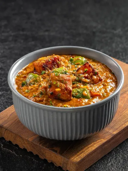 A flavorful Kadai Paneer, with chunks of paneer and bell peppers in a thick gravy. The presentation is simple and focused on the food.