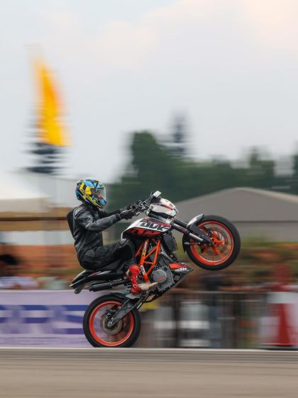 A rider performs a perfect wheelie on a KTM Duke. The control to maintain the balance point while in motion is a core skill of professional stunt riding.