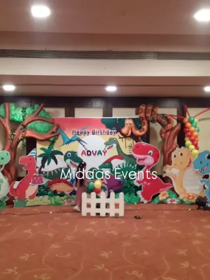 The main stage for Advay's dinosaur-themed birthday party. This setup features a large printed backdrop, friendly dinosaur cutouts, and balloon columns, creating a perfect scene for cake cutting.