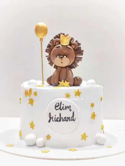 A simple and sweet first birthday cake featuring an edible lion king topper, golden stars, and a balloon. The design is clean, elegant, and adorable.