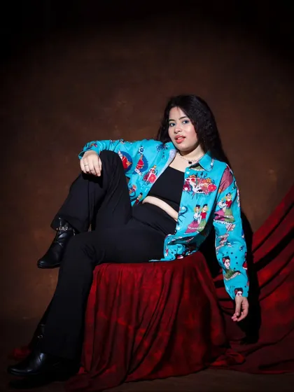 Another look in the vibrant printed shirt. This seated pose is cool and casual, with a direct and engaging look at the camera.