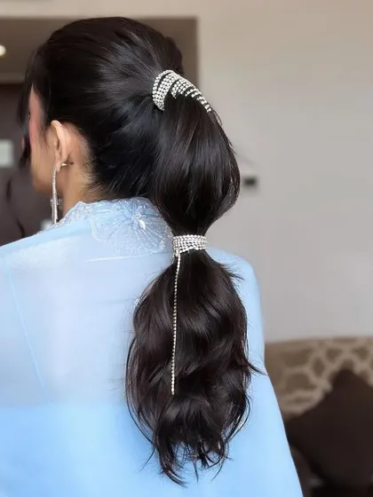 A sleek and modern bubble ponytail adorned with sparkling rhinestone accessories. This is a high-fashion, statement hairstyle perfect for a cocktail party or reception.