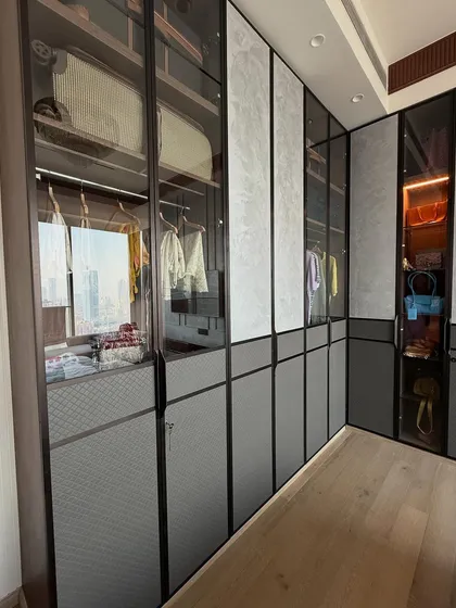 A finished walk-in wardrobe with glass and profile shutter doors. This design allows you to see your clothes easily while keeping them protected and organized.