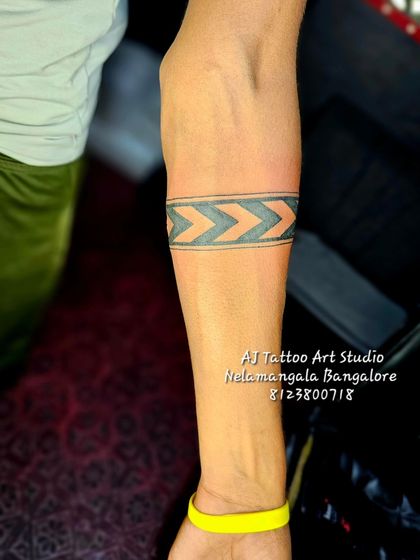 A simple but striking chevron pattern armband tattoo on the forearm.