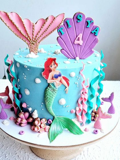 A Little Mermaid cake with a sculpted tail and seashell. The design uses 2D and 3D elements to create a fun underwater scene.