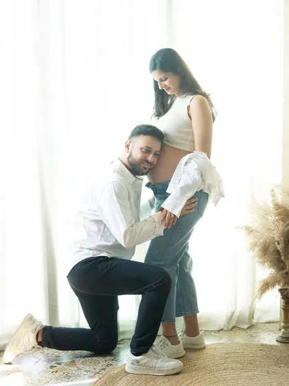 Listening for the first flutters. This casual and sweet pose during a lifestyle shoot captures the dad-to-be's excitement and connection to the baby.