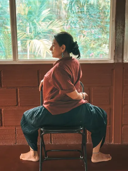 We explore how a simple chair can transform your practice and teaching. This seated spinal twist demonstrates an accessible modification for improving mobility and relieving tension in the back, suitable for students of all ages.