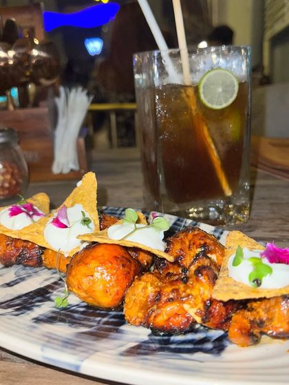 A close-up of the creatively plated chicken tikka nachos and a mocktail at Dutchman's Port, showing off their culinary fusion.