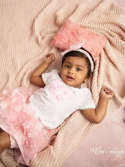 A relaxed, morning mood. This overhead shot captures a baby lying comfortably on a soft pink blanket, a sweet and simple infant portrait.