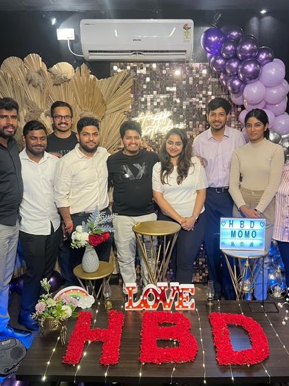 A group of friends and colleagues gather to celebrate a birthday. The "HBD MOMO" lightbox and beautiful floral "HBD" sign show the level of personalization I can offer for your event.