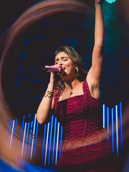 Dhvani Bhanushali lost in the music. This shot, with its creative light ring effect, captures the energy of her performance in a custom maroon lace-up jumpsuit by Seraphine Design Studio.