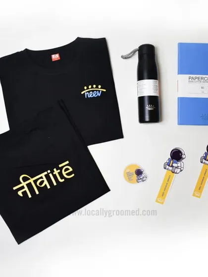 This creative welcome kit for a client includes custom-printed t-shirts with Hindi script, a water bottle, a notebook, and fun astronaut-themed bookmarks, showing our versatility in design.