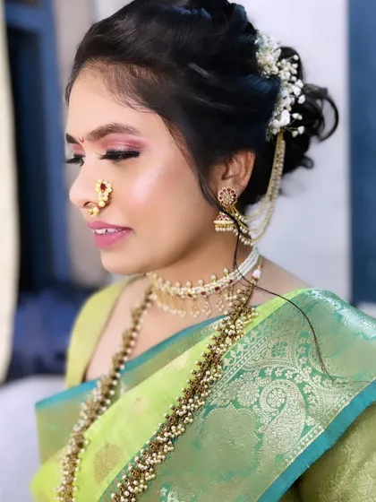 A side profile of Radhika's stunning bridal makeup. The shimmery pink eyeshadow and glowing skin create a look that is both bold and beautiful.