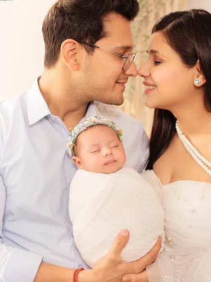A classic newborn portrait with both parents. The baby is wrapped snugly, and the parents' loving expressions complete this perfect picture.