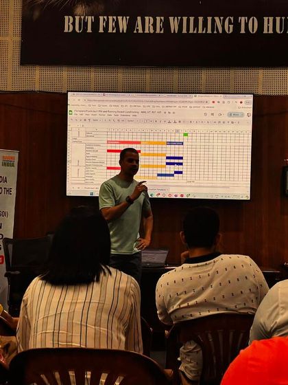 Presenting a detailed training schedule during a session with the Boxing Federation of India. The banner behind me says 'BUT FEW ARE WILLING TO HUNT', a philosophy I bring to my coaching.
