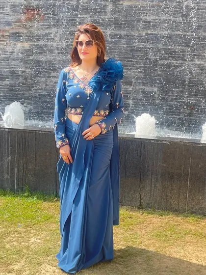 I love creating versatile pieces like this pre-stitched drape saree. It gives you the elegance of a saree with the comfort of a gown. The floral embroidered blouse and the 3D flower on the shoulder make it a true statement piece for any party.