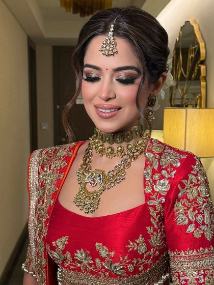 This bride is wearing a classic low bun adorned with white roses for her wedding day. The look is clean, elegant, and perfectly complements her traditional red attire.