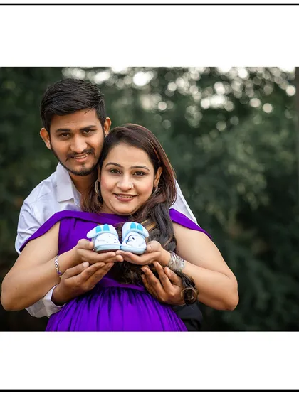 The couple proudly presenting a pair of tiny baby shoes. This is a classic prop that symbolizes the new life they are waiting for.