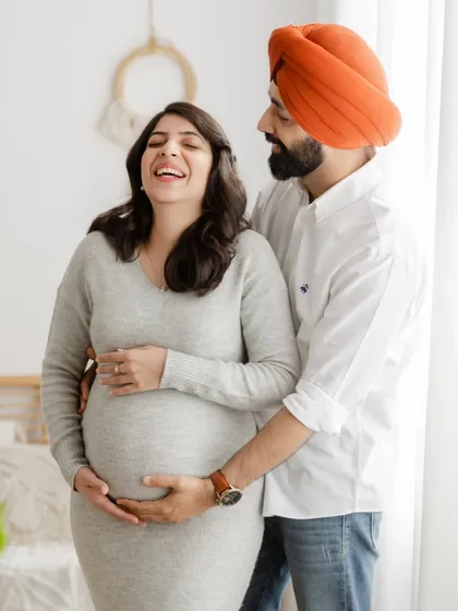 We love capturing pure, unscripted joy. This candid shot of an expecting couple sharing a laugh during their lifestyle maternity shoot shows the genuine connection we aim to photograph.