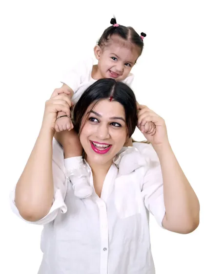 A mother and daughter portrait, with the little girl sitting happily on her mom's shoulders.