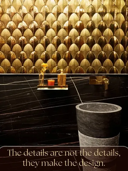 I live by the principle that the details are not just details; they make the design. This powder room is a testament to that belief, with intricate golden fish-scale tiles creating a textured, reflective wall that contrasts beautifully with the dark marble and stone basin.