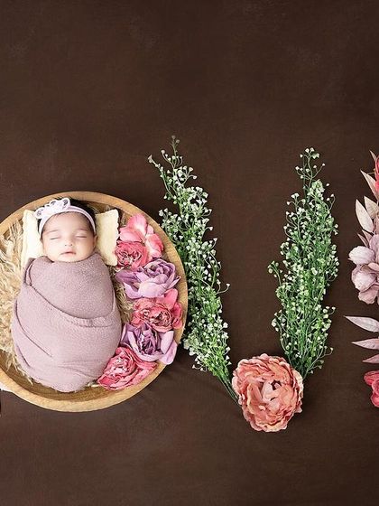 Spelling out L-O-V-E with flowers. This creative flat-lay shot features a newborn nestled in the 'O', creating a beautiful and artistic birth announcement.