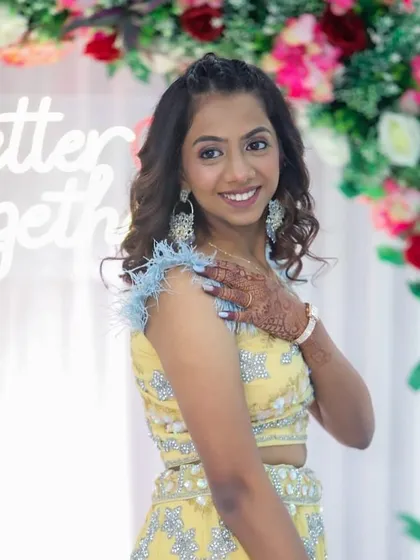 A side profile showing her soft curls and the pretty floral background of the event.